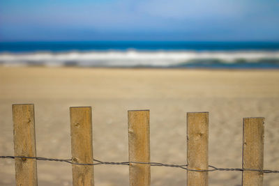 Low angle view of fence on beach against sky