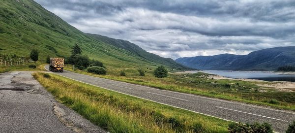 Scenic view of road by mountains against sky