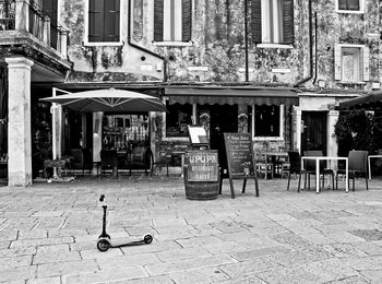 Chairs and tables on sidewalk by buildings in city