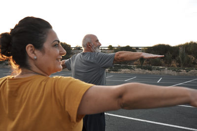 An older couple practices yoga outdoors.