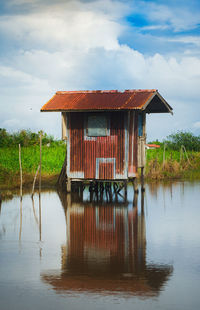 House by lake against sky