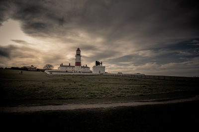 Lighthouse amidst buildings against sky
