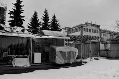 Snow covered field by buildings against sky
