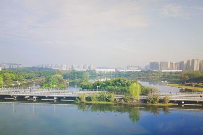 Cityscape by river against sky