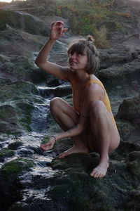 Low section of woman on the rock playing with water