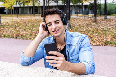 Man listening music while using mobile phone in city