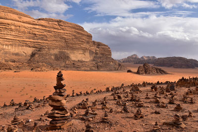 Red rock formations on wadi rum landscape against cloudy sky