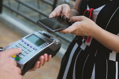 Midsection of woman making mobile payment in store