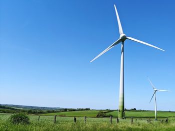 Windmill on field against clear blue sky