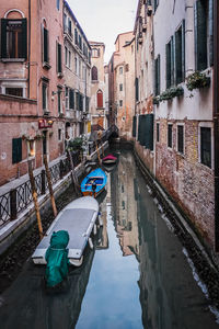 Boats moored in canal amidst buildings