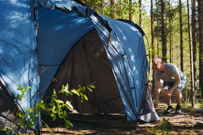 Caucasian man wearing a hat putting up a tent. family camping concept