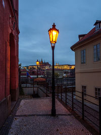 Street lights on footpath by buildings at dusk