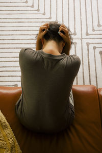 Directly above view of lonely woman sitting on sofa at home