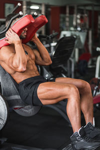 Midsection of man with arms raised training in gym leg workout