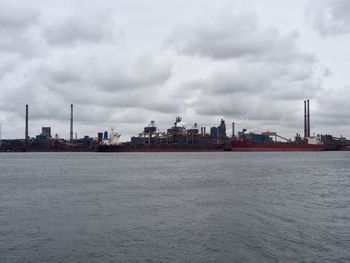 Sea by buildings against sky in city