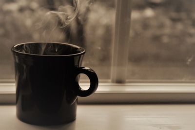 Close-up of coffee cup on window sill