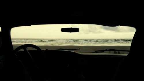 Silhouette boat on calm beach against sky at dusk