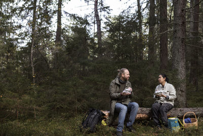 Friends sitting on land in forest