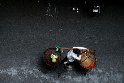 High angle view of vendor carrying baskets while walking on street