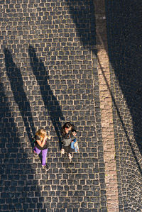 High angle view of friends standing on cobblestone street