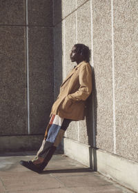 Full length of young woman standing against wall