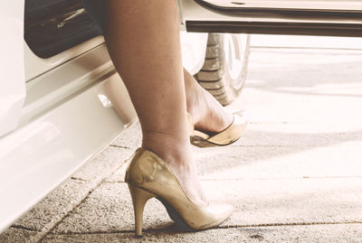 Low section of woman disembarking from car on street