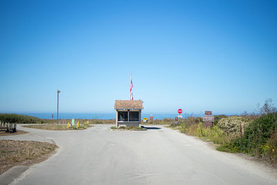 Empty road by street against clear blue sky