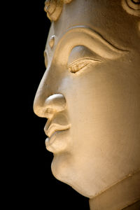 Low angle view of the statue of the buddha on a black background.