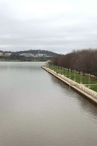 Scenic view of river by city against sky