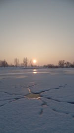 Scenic view of frozen lake against sky during sunset