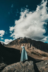 Rear view of person on rock against sky