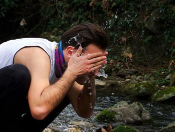 Close-up of man washing face with water at lake