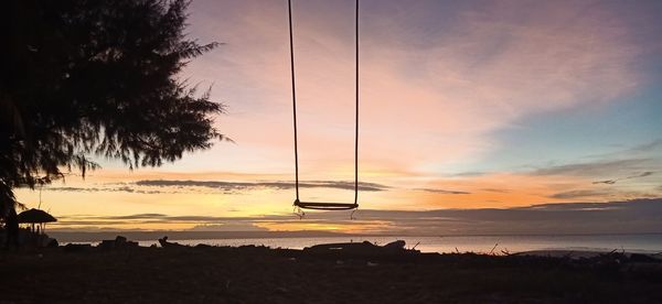 Silhouette trees on beach against sky during sunset