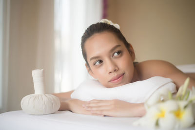 Smiling young woman lying on massage table in spa