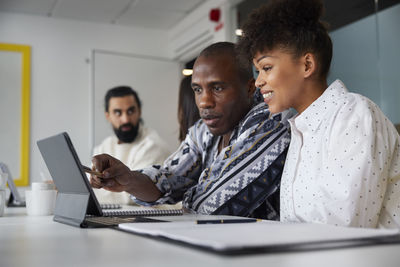 Coworkers sitting at business meeting and looking at digital tablet