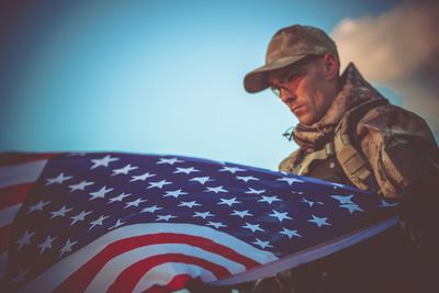 Soldier with american flag against sky