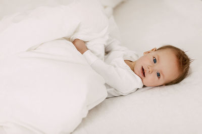 Portrait of cute baby lying on bed at home