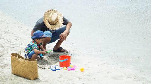 Father and son playing with toy on sand at beach