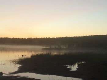 Scenic view of lake against clear sky during sunset