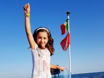 Portrait of happy girl standing against clear blue sky