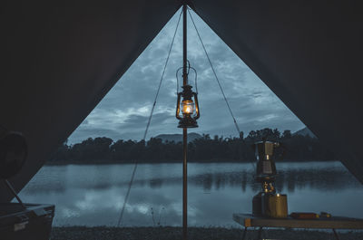 Reflection of illuminated tower in lake against sky at dusk