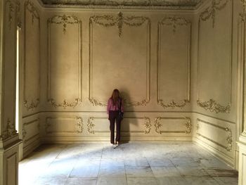 Rear view of woman standing against wall