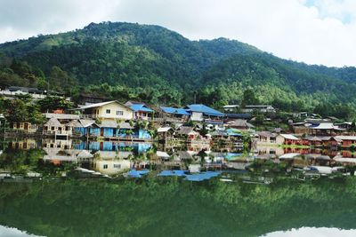 Houses by lake against sky