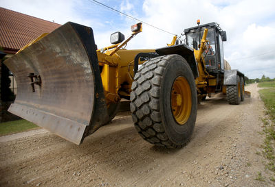 Construction vehicle on dirt road against sky