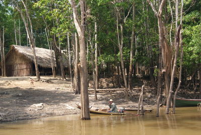 People sitting on riverbank in forest