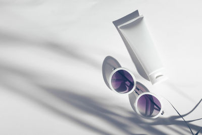 High angle view of moisturizer bottle and sunglasses against white background