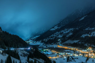 Illuminated townscape against mountains at night