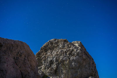 Low angle view of rock formation against clear blue sky