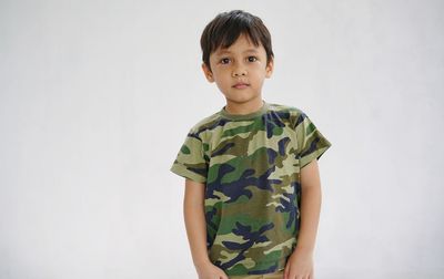 Portrait of cute boy standing against white background