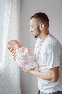 Side view of man holding baby girl at home